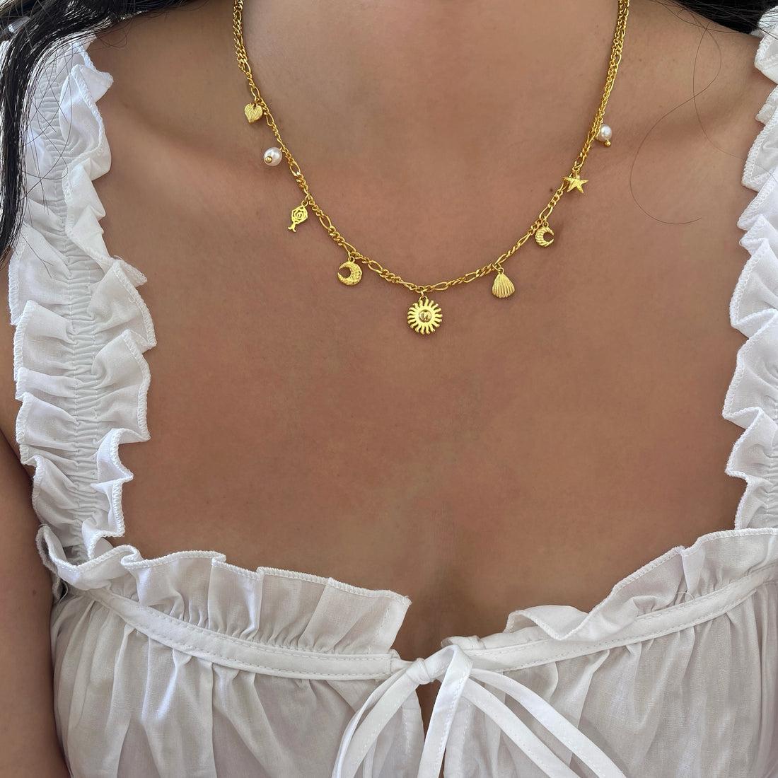 Oplev Ocean Heart Halskæde fra Pallantis Smykker – en 24 karat forgyldt sølvkæde med vedhæng som en sol, søstjerne, rose, muslingeskal, halvmåner og to ferskvandsperler. Inspireret af havets skønhed.