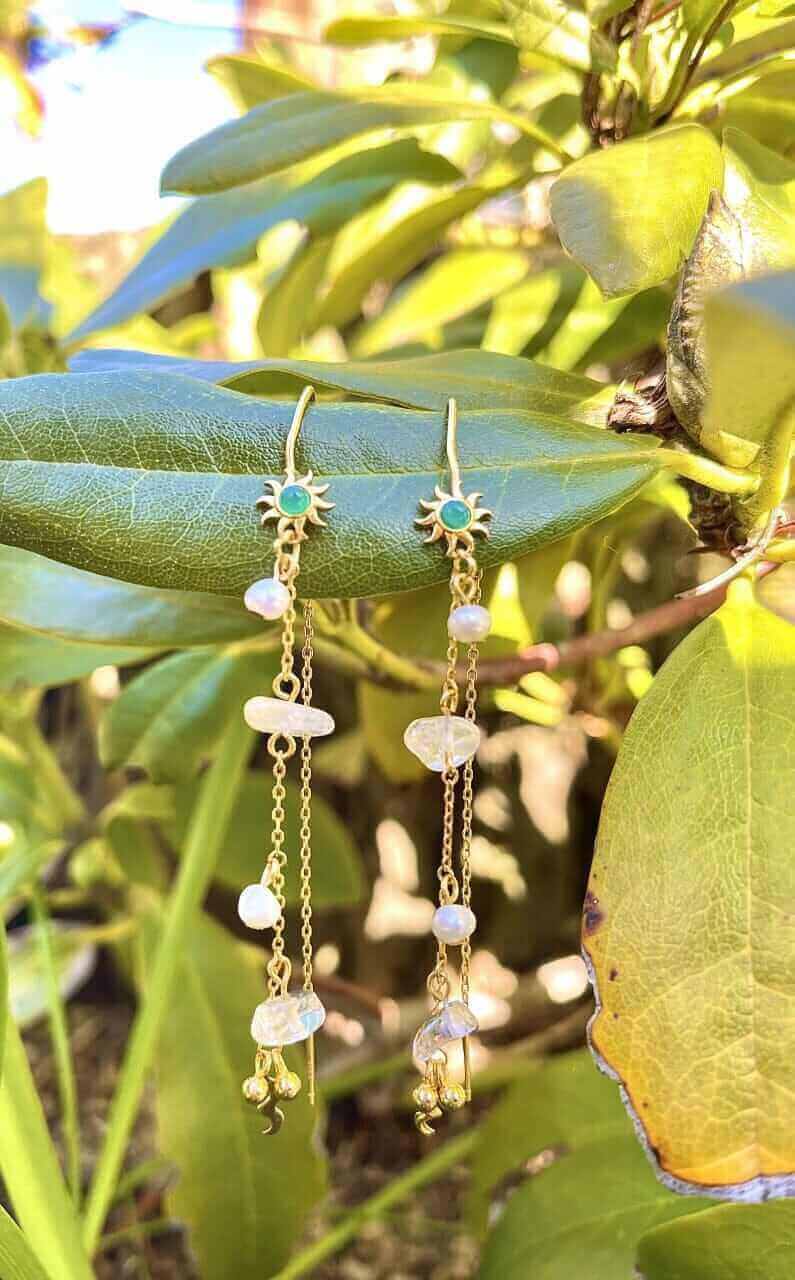 Pallantis Grønne Sol Øreringe har solformede grønne sten, ferskvandsperler, gennemsigtige perler og små guldvedhæng, alle elegant ophængt i tynde guldkæder.