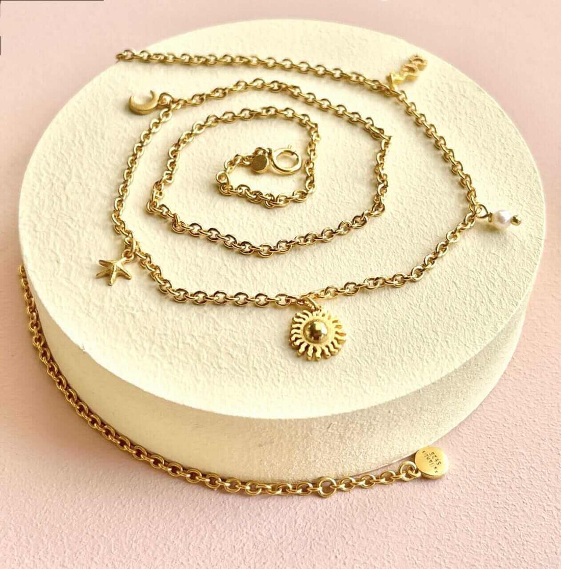 Luna Halskæden fra Pallantis er en guldhalskæde med 18 karat guldforgyldning, med fem himmelske charme – halvmåne, stjerne, sol, planet og perle – og måne og stjerne vedhæng for et finurligt præg.